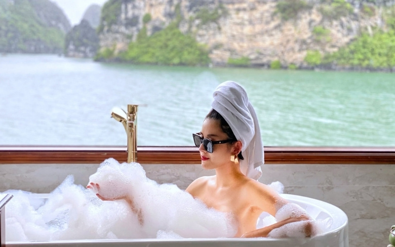 Ngâm mình trong bồn tắm, bên cạnh khung cửa kính panorama